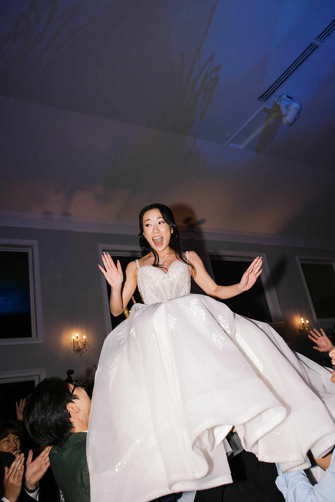 A bride being picked up on a chair laughing during the wedding reception at the view at bluemont in virginia. 