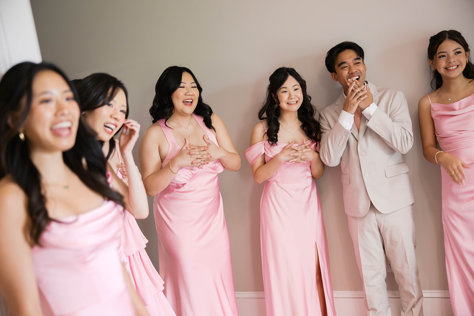 Bridesmaids wearing pink looking shocked at seeing the bride in her dress at the view at bluemont.
