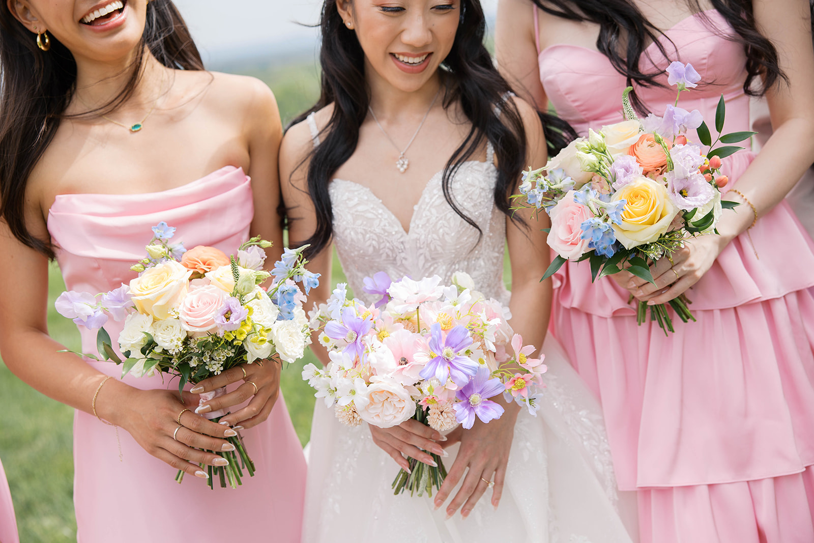 Bridesmaids wearing pink dresses holding their colorful bouquets at a wedding in bluemont virginia during the day