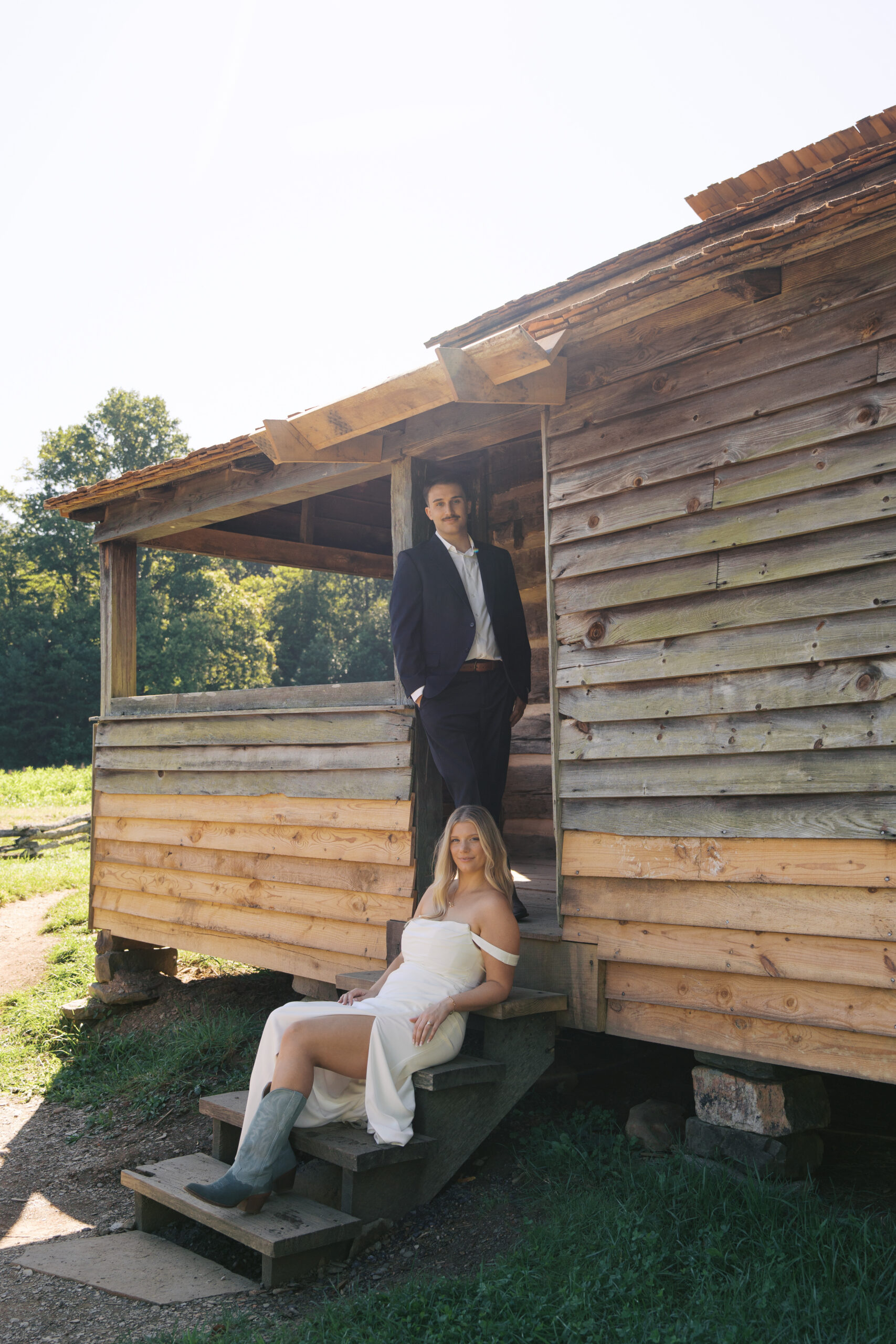 A bride sitting on a porch stoop with a groom standing next to her during their great smoky mountains elopement