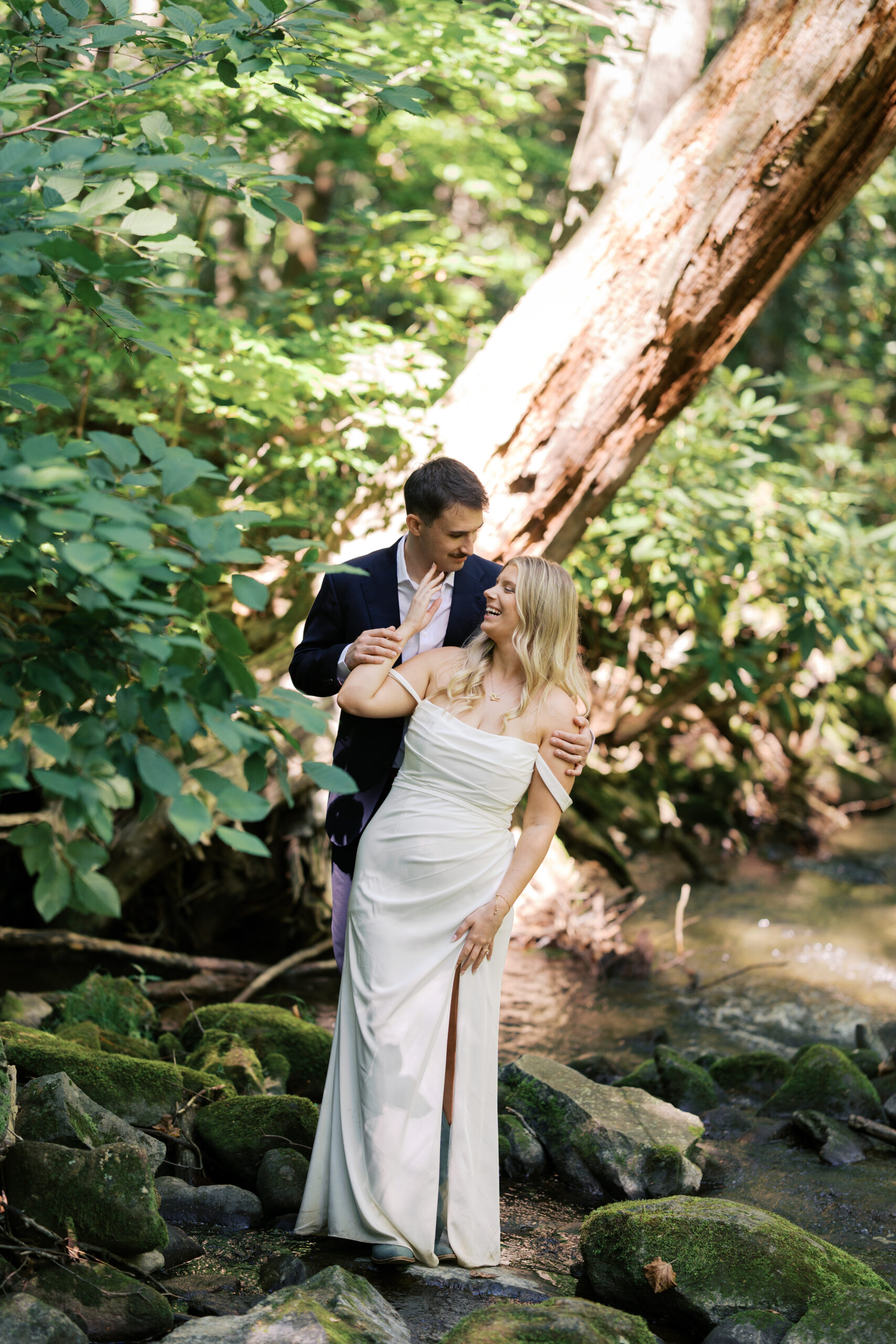 A bride and groom looking at each other laughing in a creek at great smoky mountains national park during their elopement