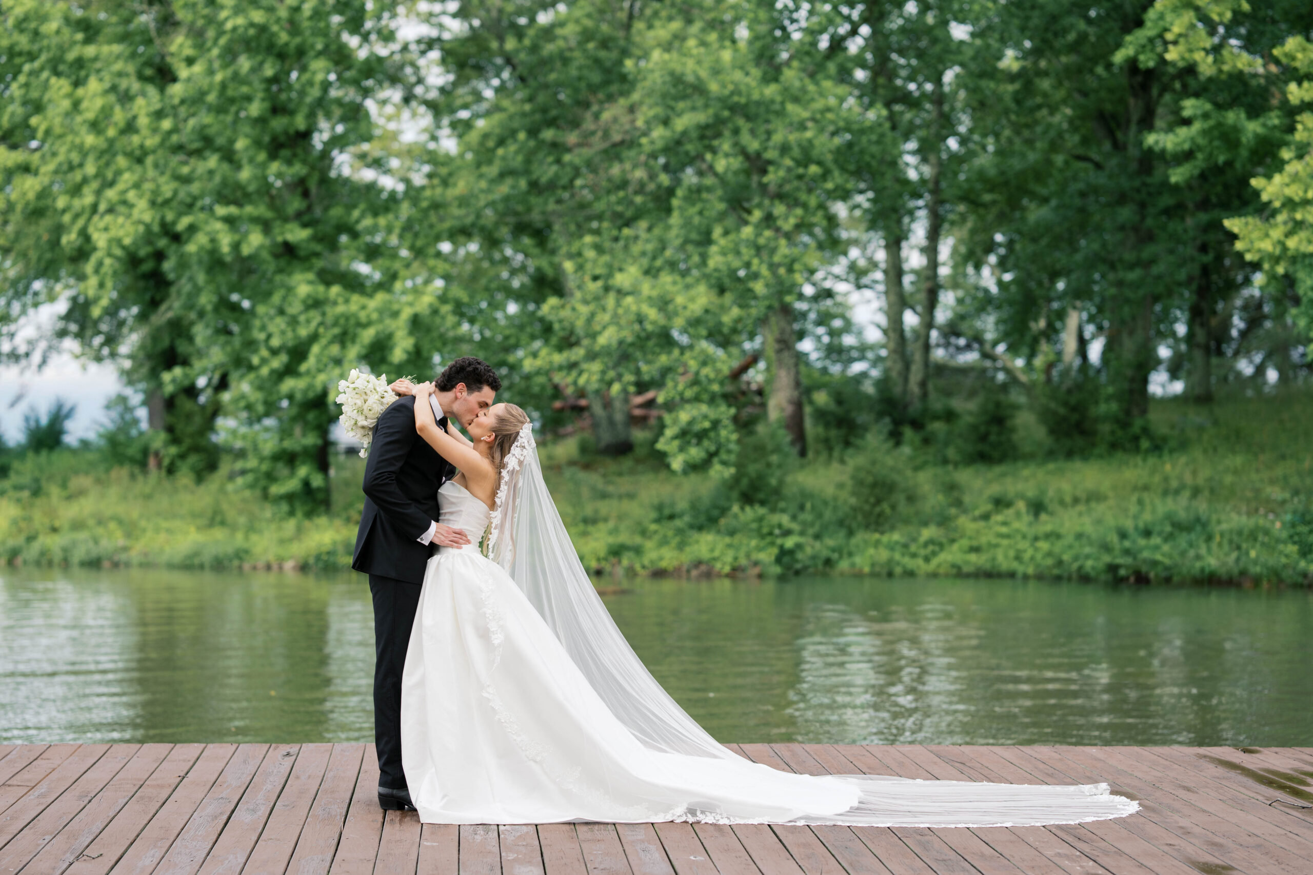 A bride and groom kissing on a dock at Cherokee Dock wedding venue in Lebanon Tennessee. Photograph by Jaimee Raneigh Photography. 