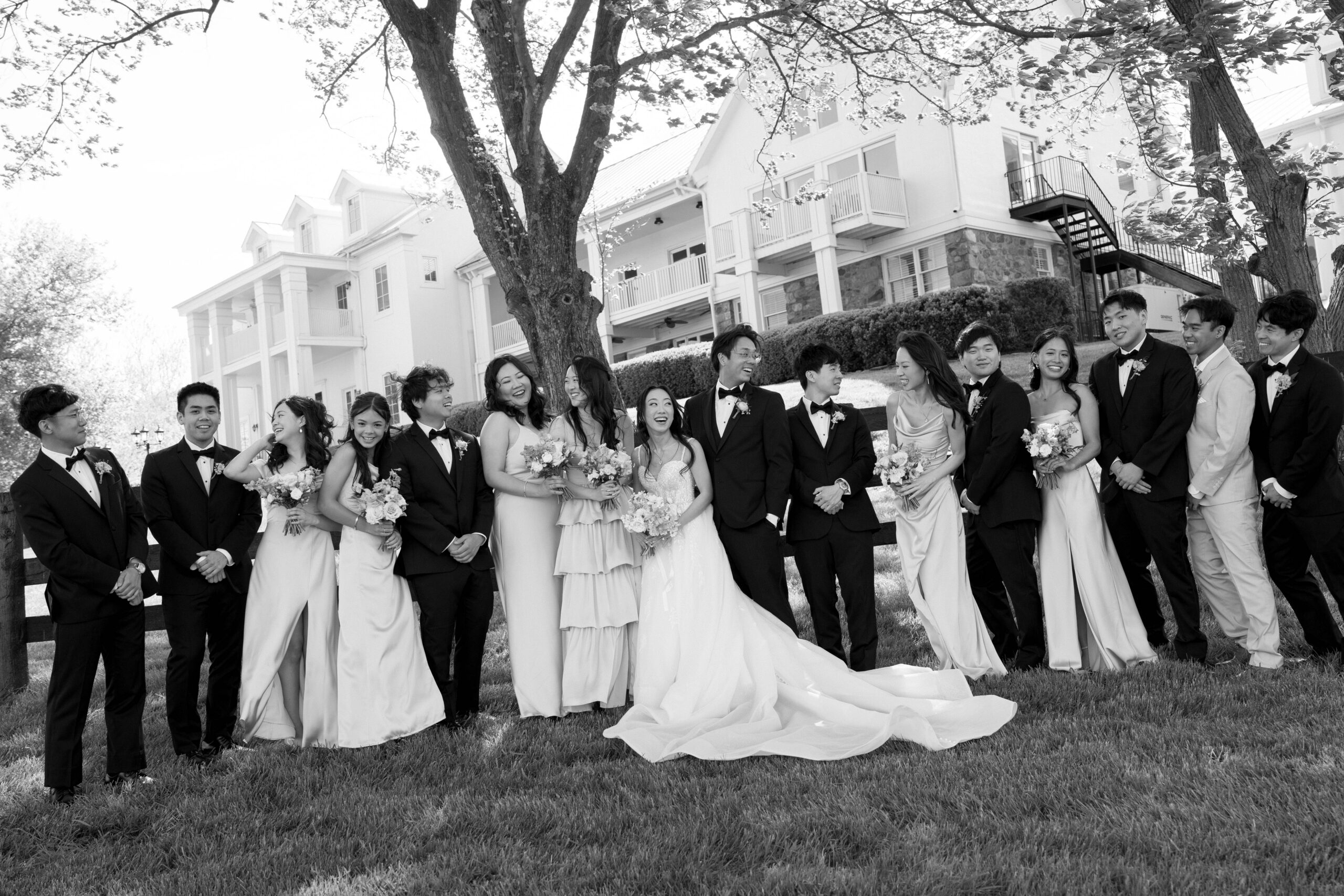 A couple with their large bridal party looking at each other laughing at their luxury wedding venue