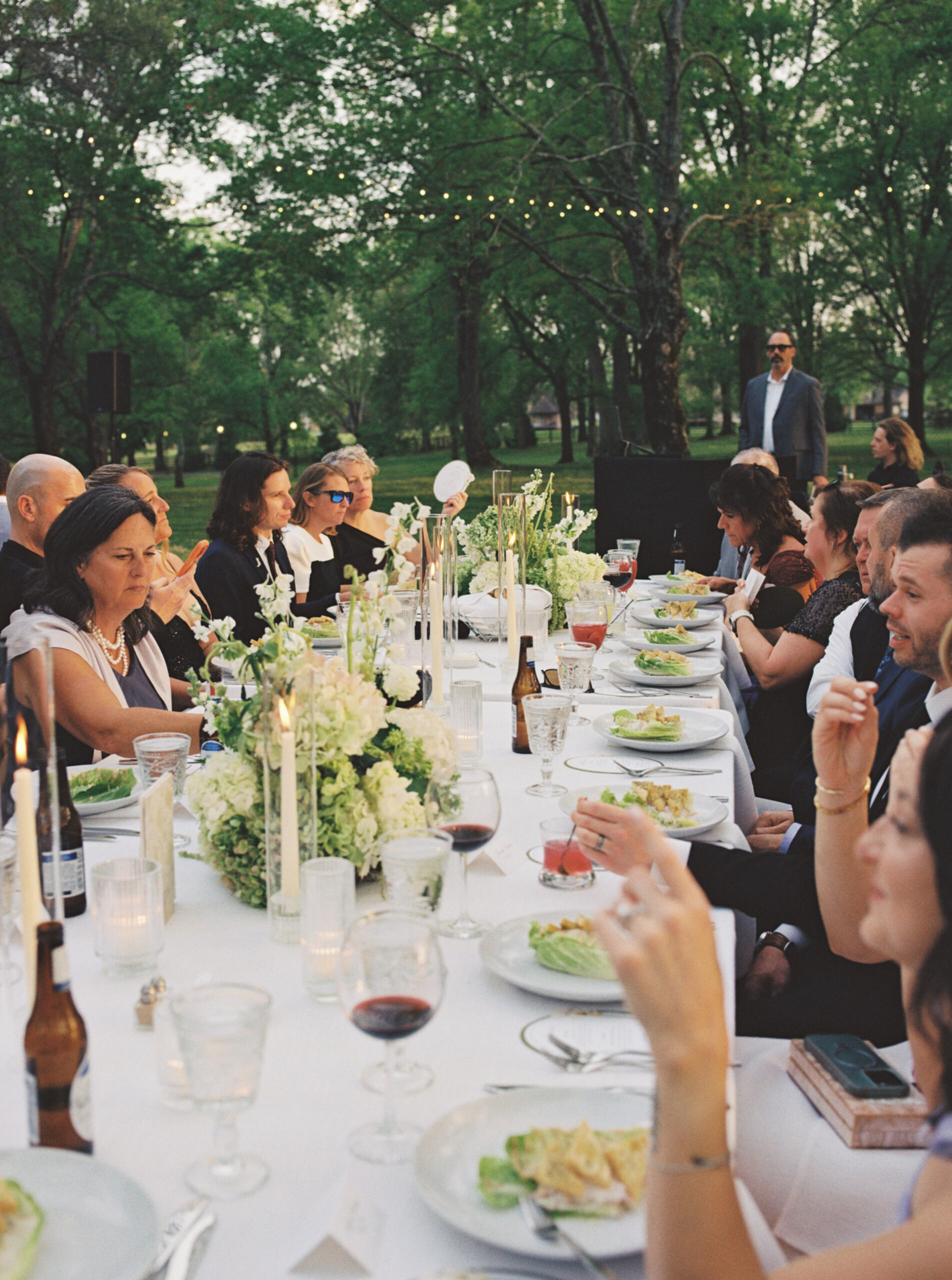 A film photo of guests interacting at dinner during a wedding reception at the estate at cherokee dock. photography by jaimee raneigh. 
