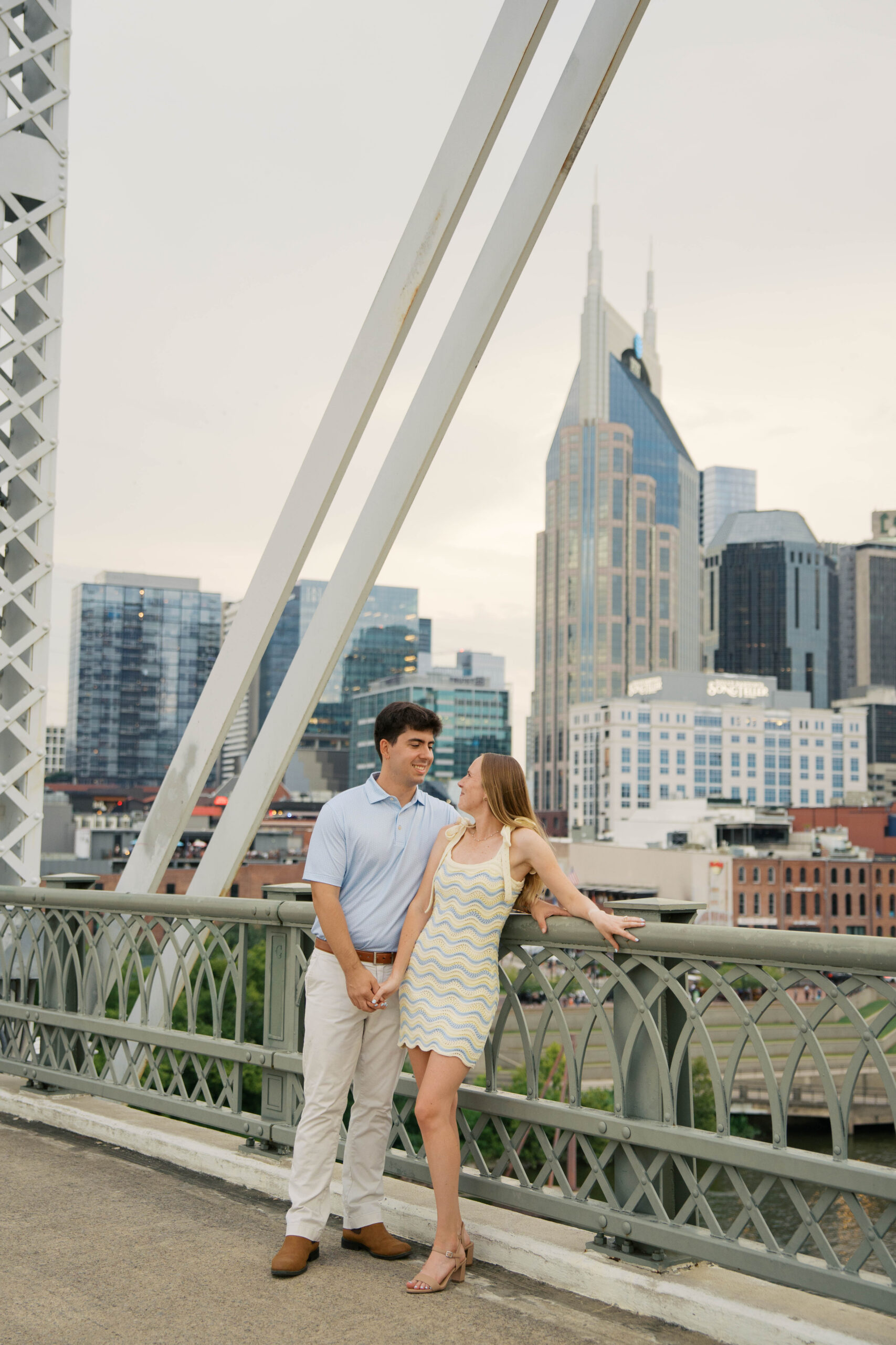 A couple standing on the pedestrian bridge in nashville Tennessee during their engagement session.