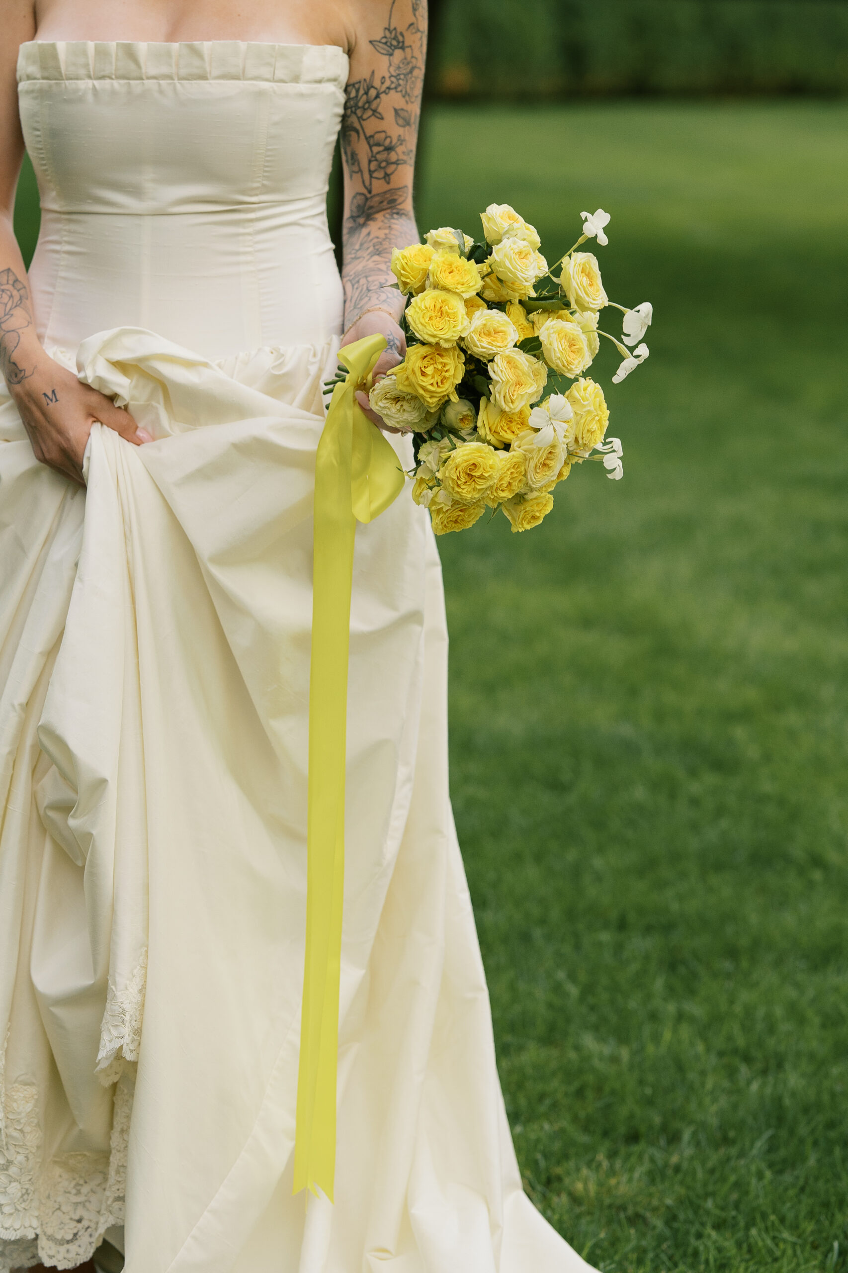 A bride at the mount wedding venue holding a bouquet of yellow roses.