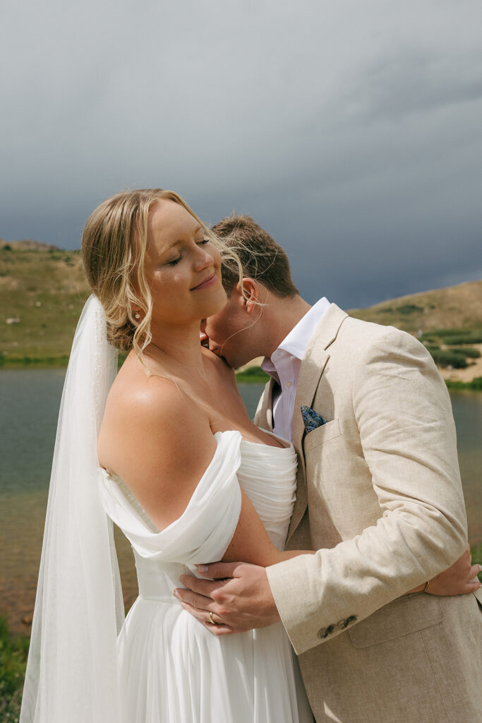 groom kissing the bride on the shoulder