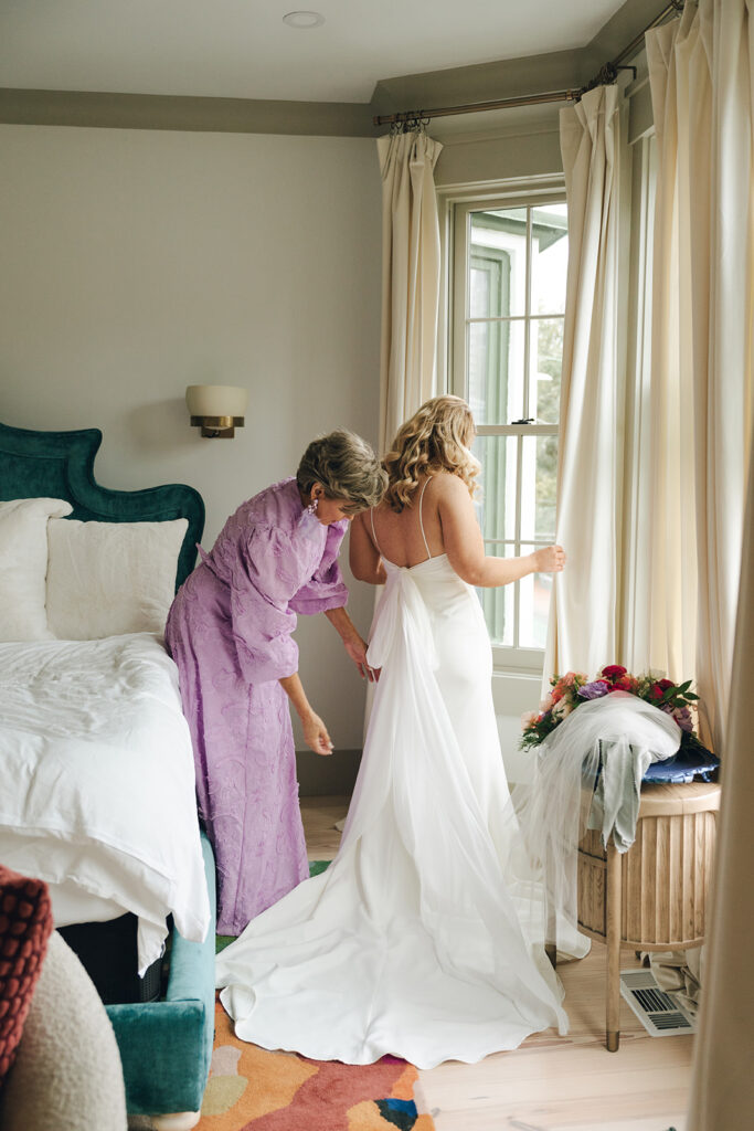 mother of the bride helping her with her wedding dress