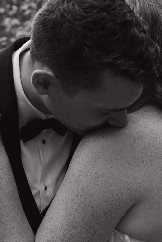 groom kissing the bride on the shoulder