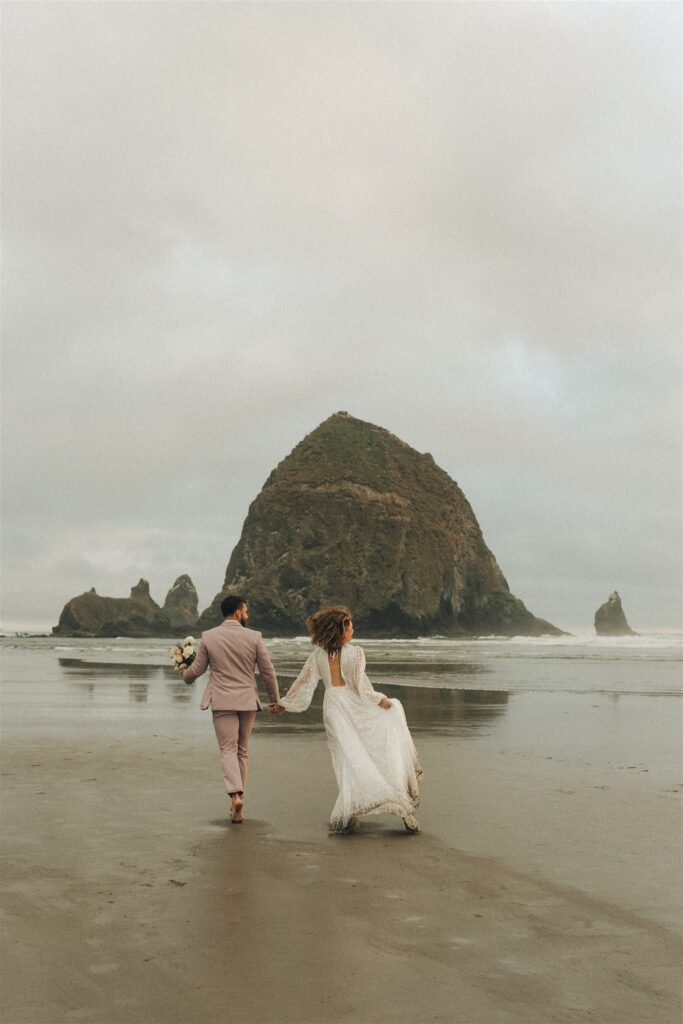 couple walking around the beach during their oregon coast elopement 