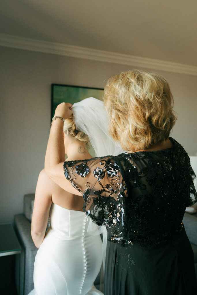 mother of the bride helping her with the wedding dress