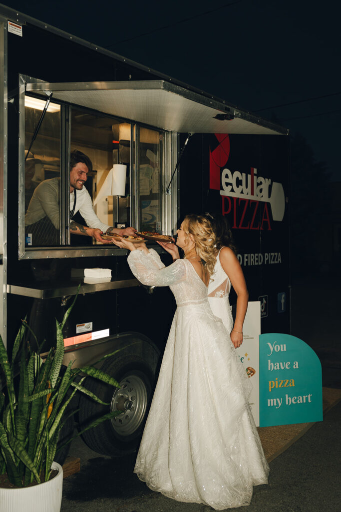 brides eating pizza at their reception