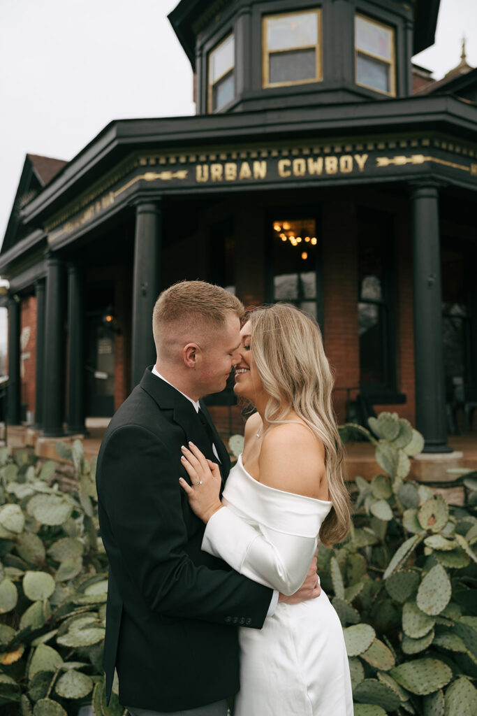 couple smiling and almost kissing at the urban cowboy with cacti in the background 