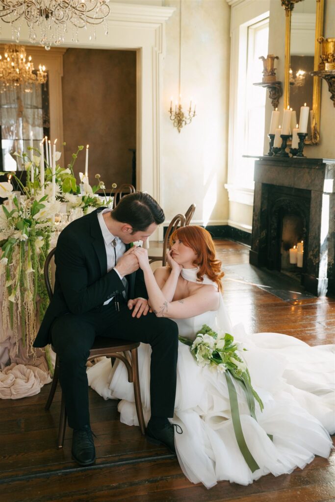 editorial bridal couple sitting and kissing hand 