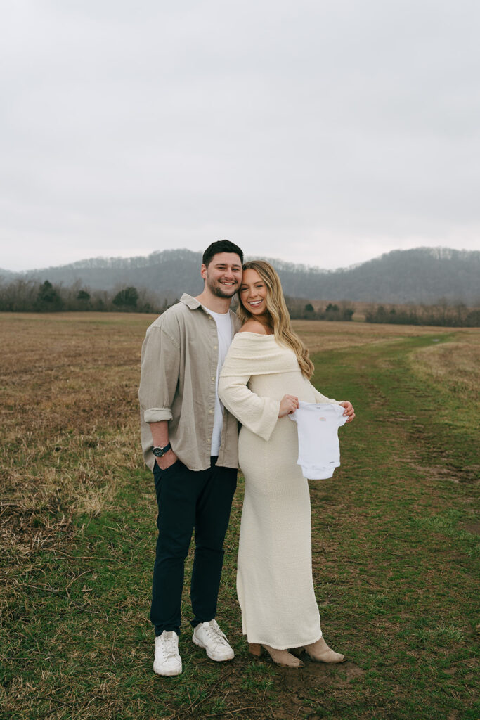 nashville couple holding baby onesie at maternity photoshoot