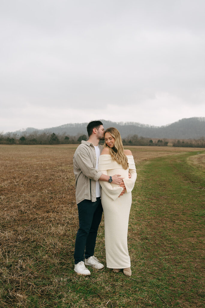 man giving pregnant wife kiss on the forehead at maternity session 