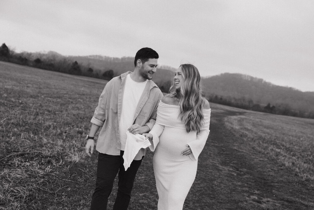 happy couple walking with baby onesie in black and white photo with dutch angle 