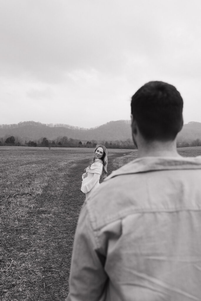 black and white photo of a man looking at his pregnant wife 