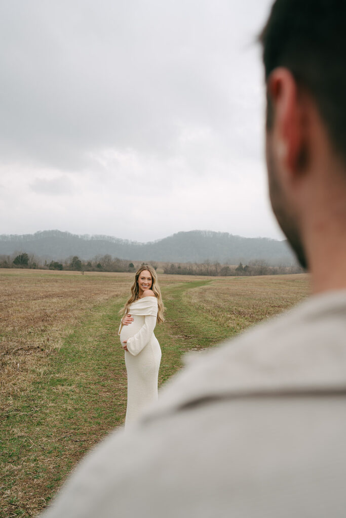 man looking at pregnant wife in a field in Nashville 