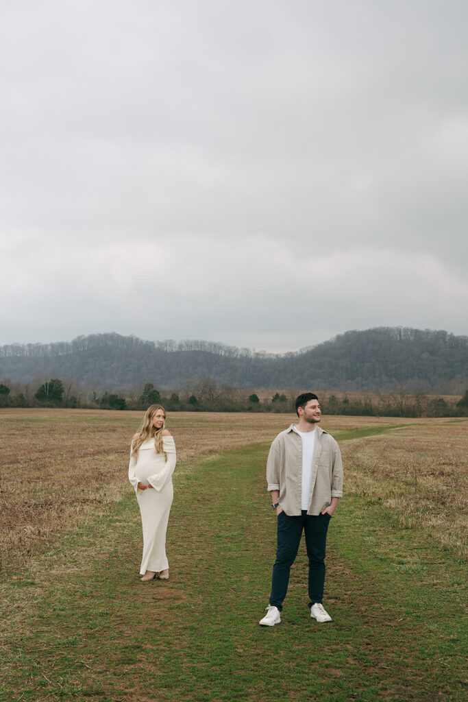man and woman standing in a field looking away from each other in winter