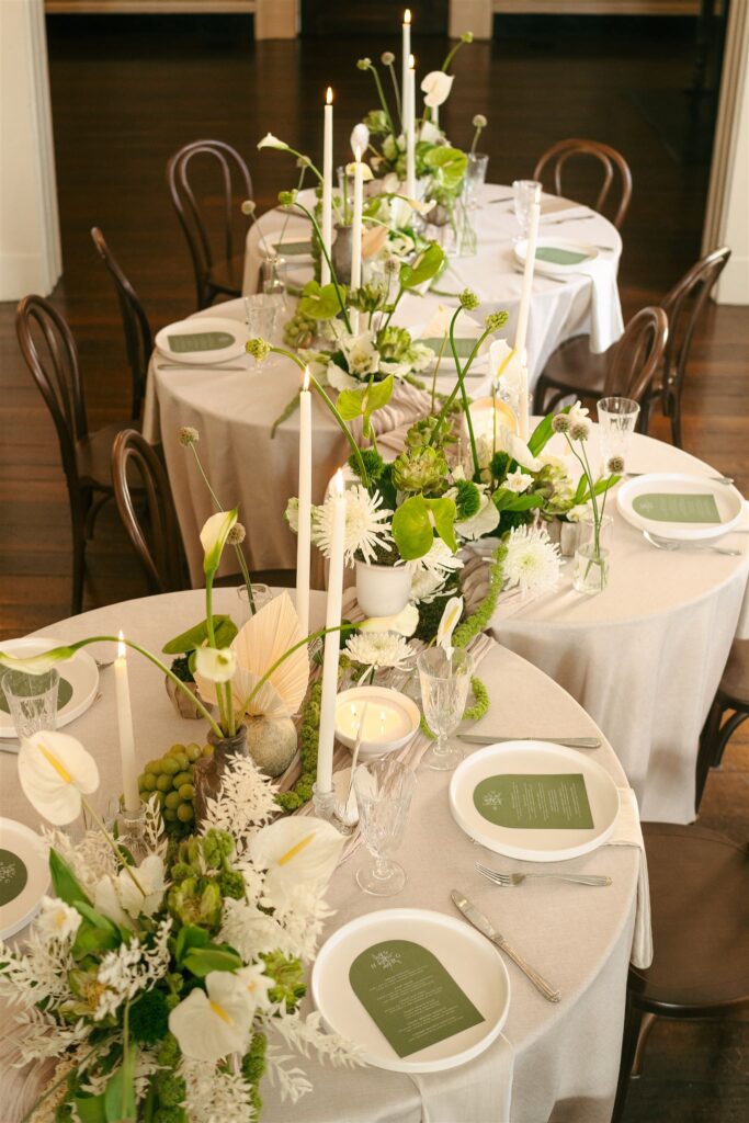 serpentine table at wedding reception with green florals and candles