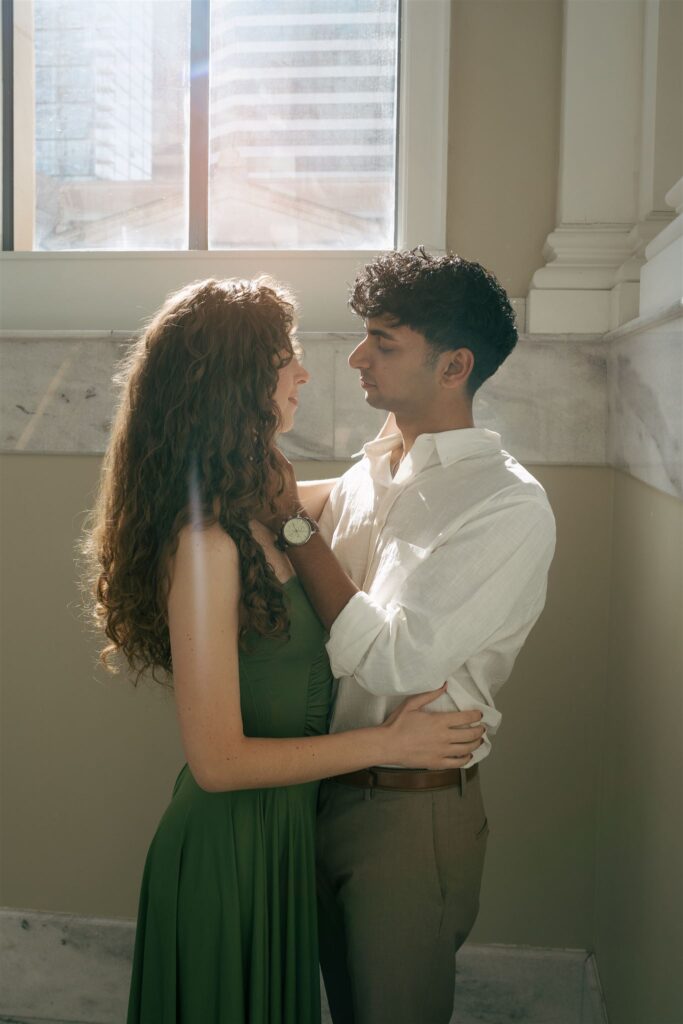 couples romantically looking at each other and holding each other while a sun flare comes through the window
