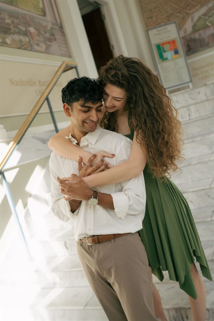 woman in green hugging her fiance from behind 