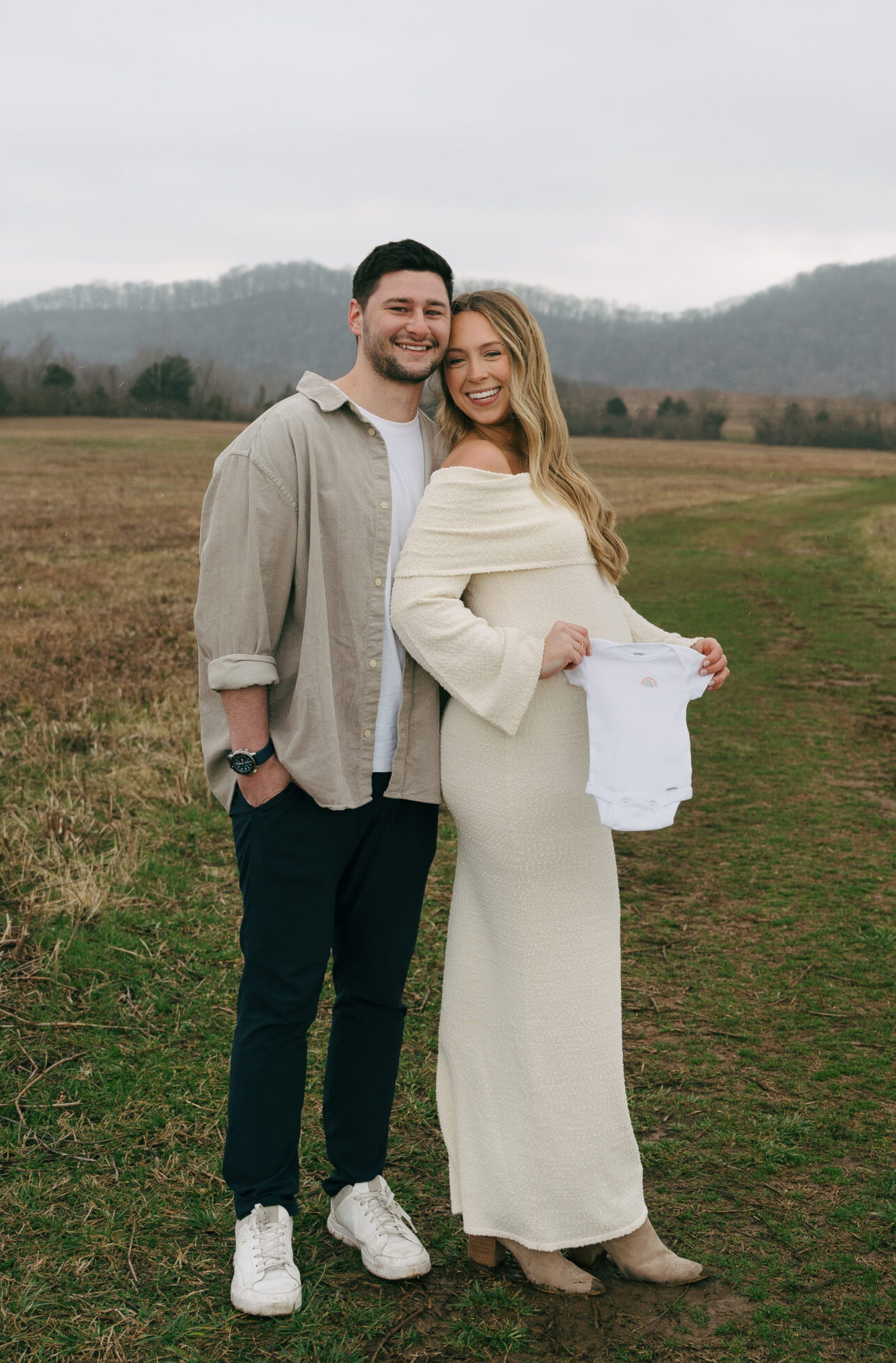 mother and father standing together holding a onesie