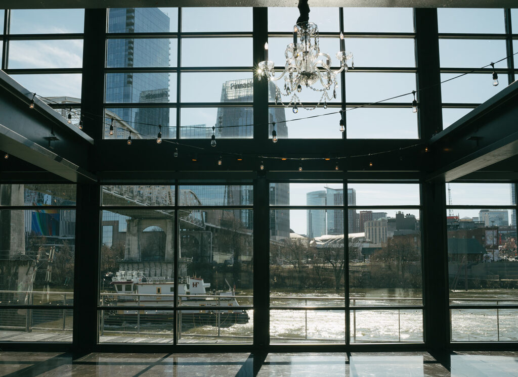 large industrial window with chandelier and natural light coming through at Tennessee wedding venue